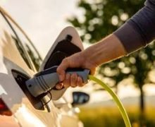 Main d’un homme branchant une voiture électrique sur une borne de recharge résidentielle installée au Québec.