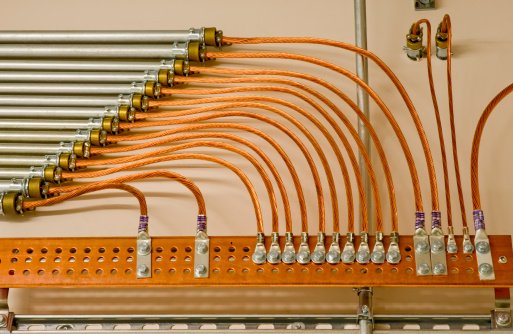 Système de mise à la terre commerciale montrant plusieurs conducteurs reliés à une barrette de terre en cuivre dans un panneau électrique.
